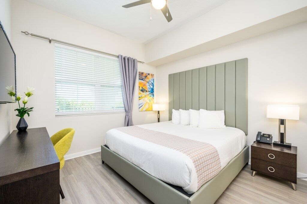 Ein modernes Schlafzimmer mit Bett, Nachttisch, Lampe und Schreibtisch mit Stuhl.