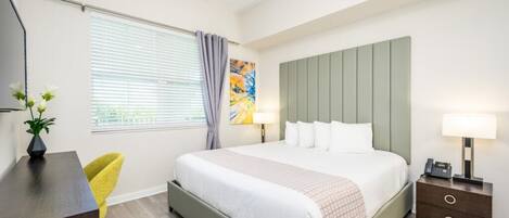 Ein modernes Schlafzimmer mit Bett, Nachttisch, Lampe und Schreibtisch mit Stuhl.