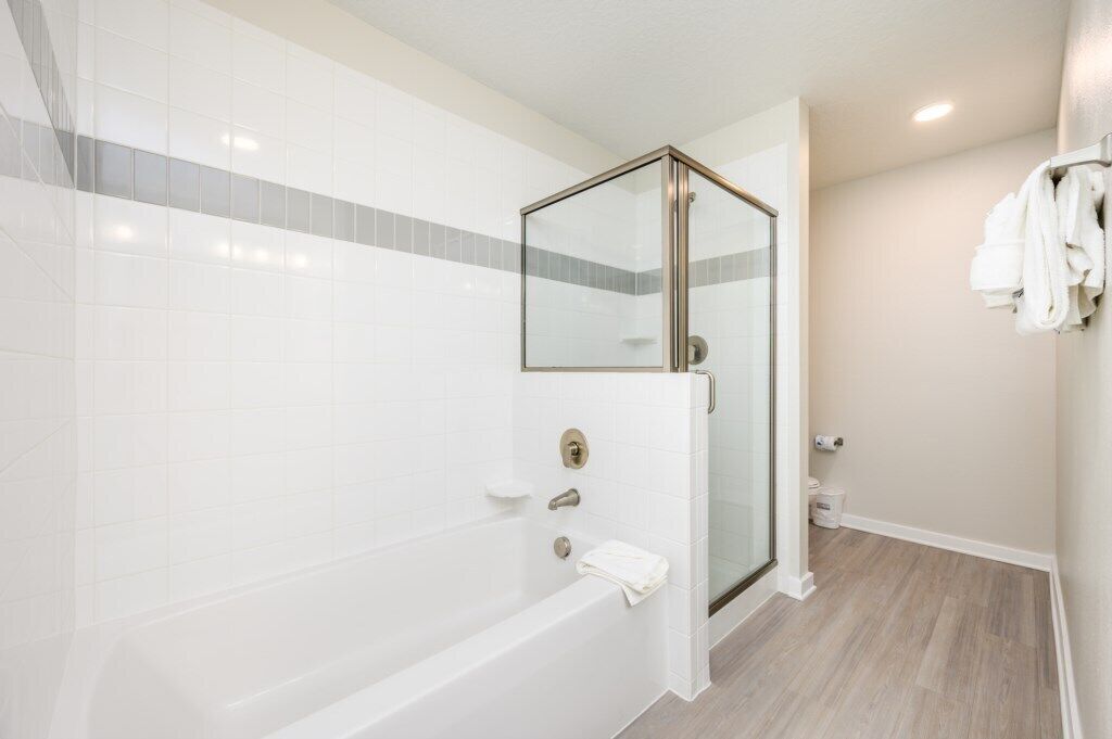 Un baño moderno con ducha de vidrio, una bañera blanca y un inodoro.