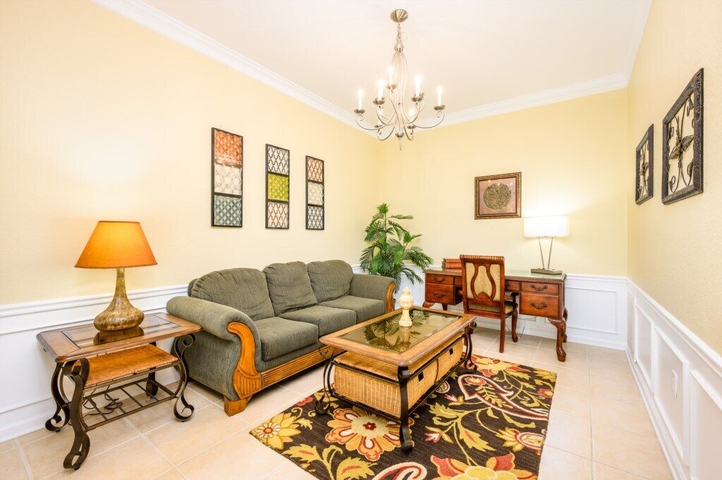 A living room with a sofa, a coffee table, a lamp, a plant, and a decorative rug.