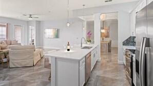 Uma cozinha moderna com ilha central, eletrodomésticos de aço inoxidável e uma área de refeições com vista.