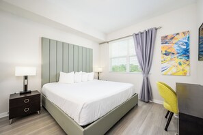 A modern bedroom with a bed, bedside tables, a desk, and a window with curtains. - Brand New Modern Vista Cay Reserve Condo - 5008 (Orlando)
