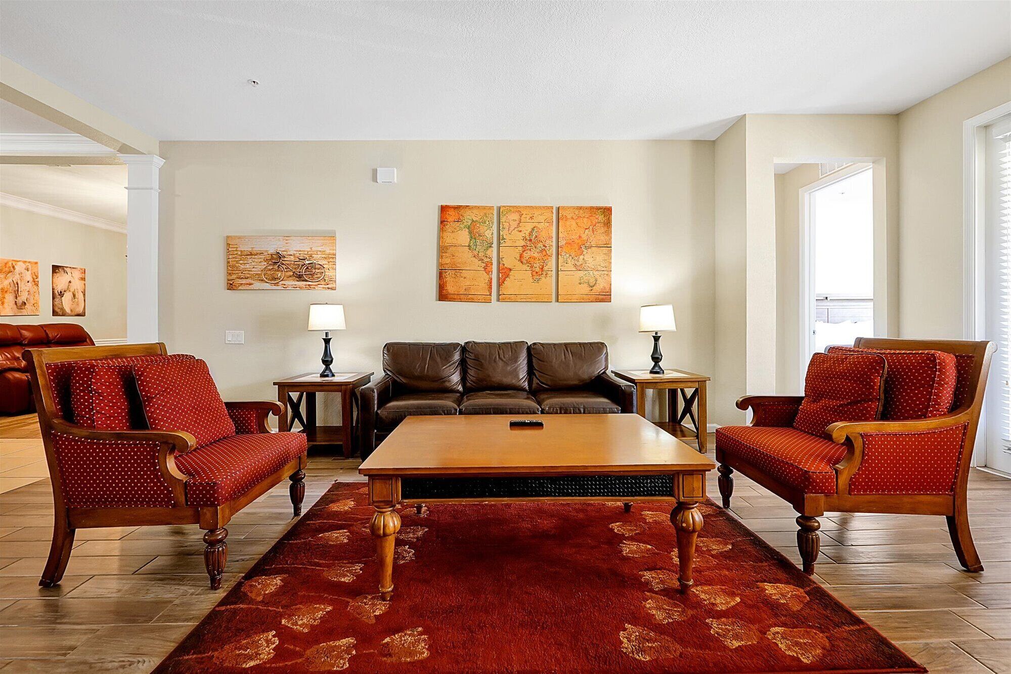 A living room with a wooden coffee table, two leather sofas, and patterned armchairs.