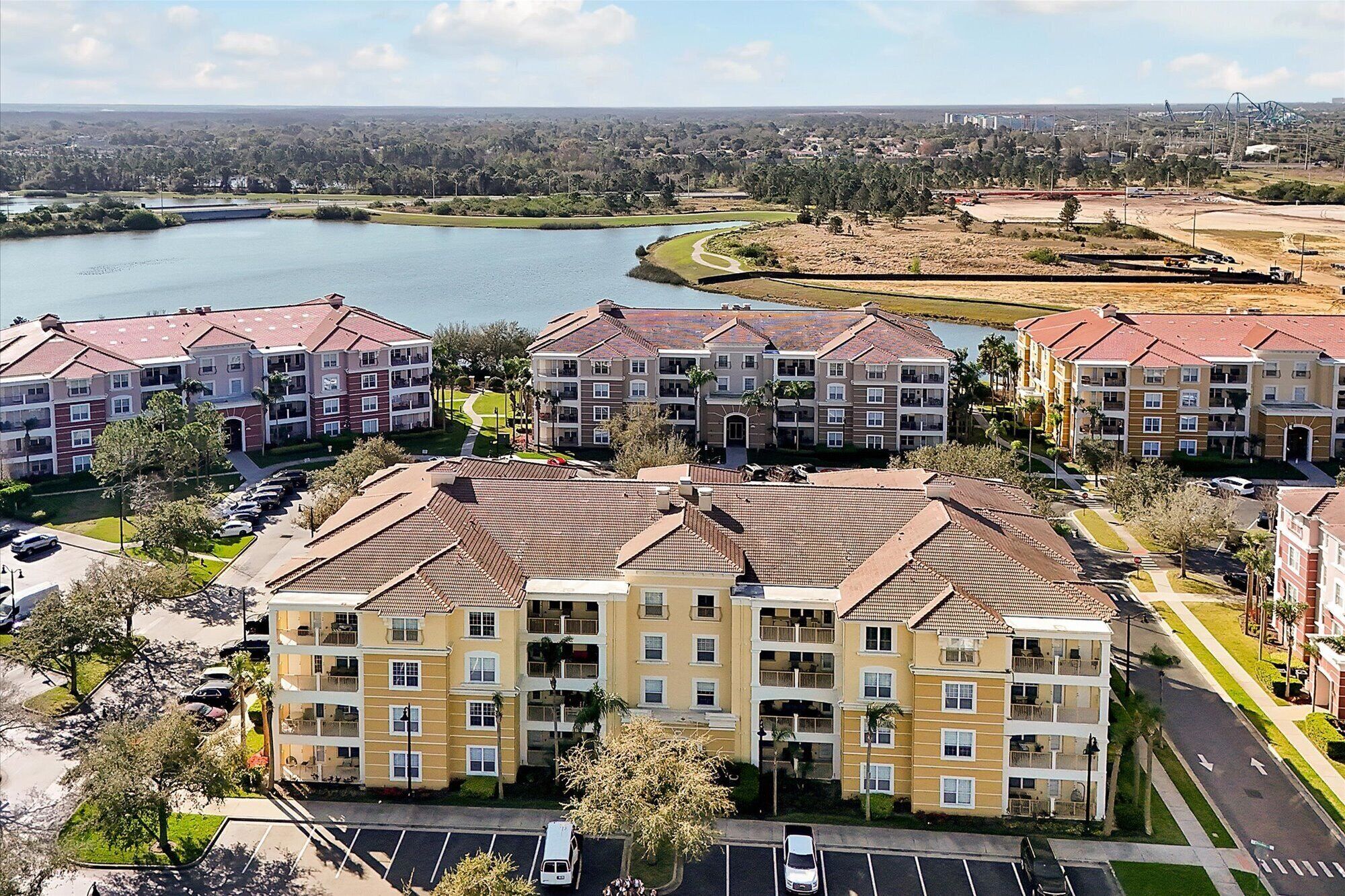 A multi-story residential building with a central courtyard, surrounded by a parking lot and a river.