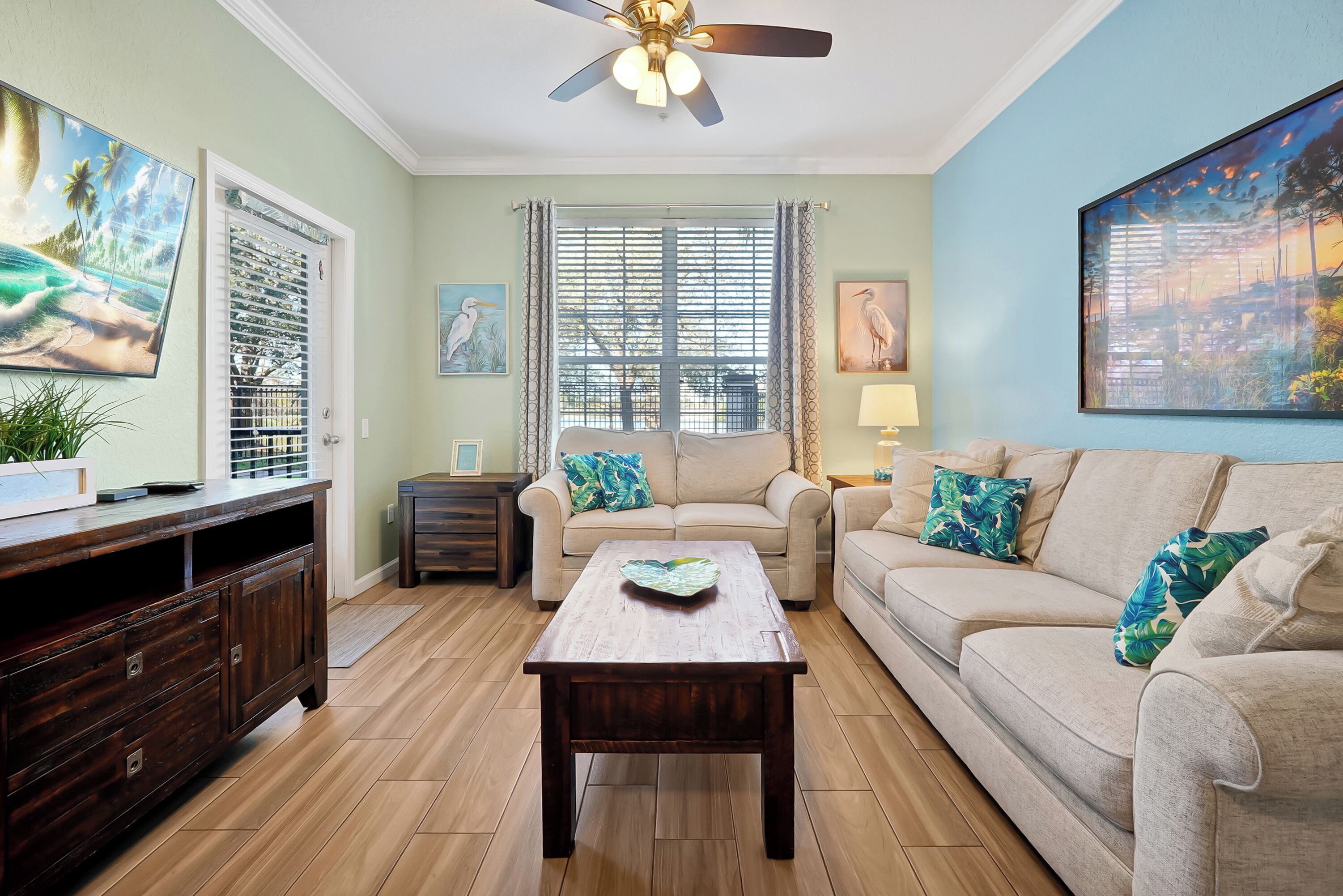 A living room with a wooden coffee table, two sofas, a TV, and a ceiling fan.