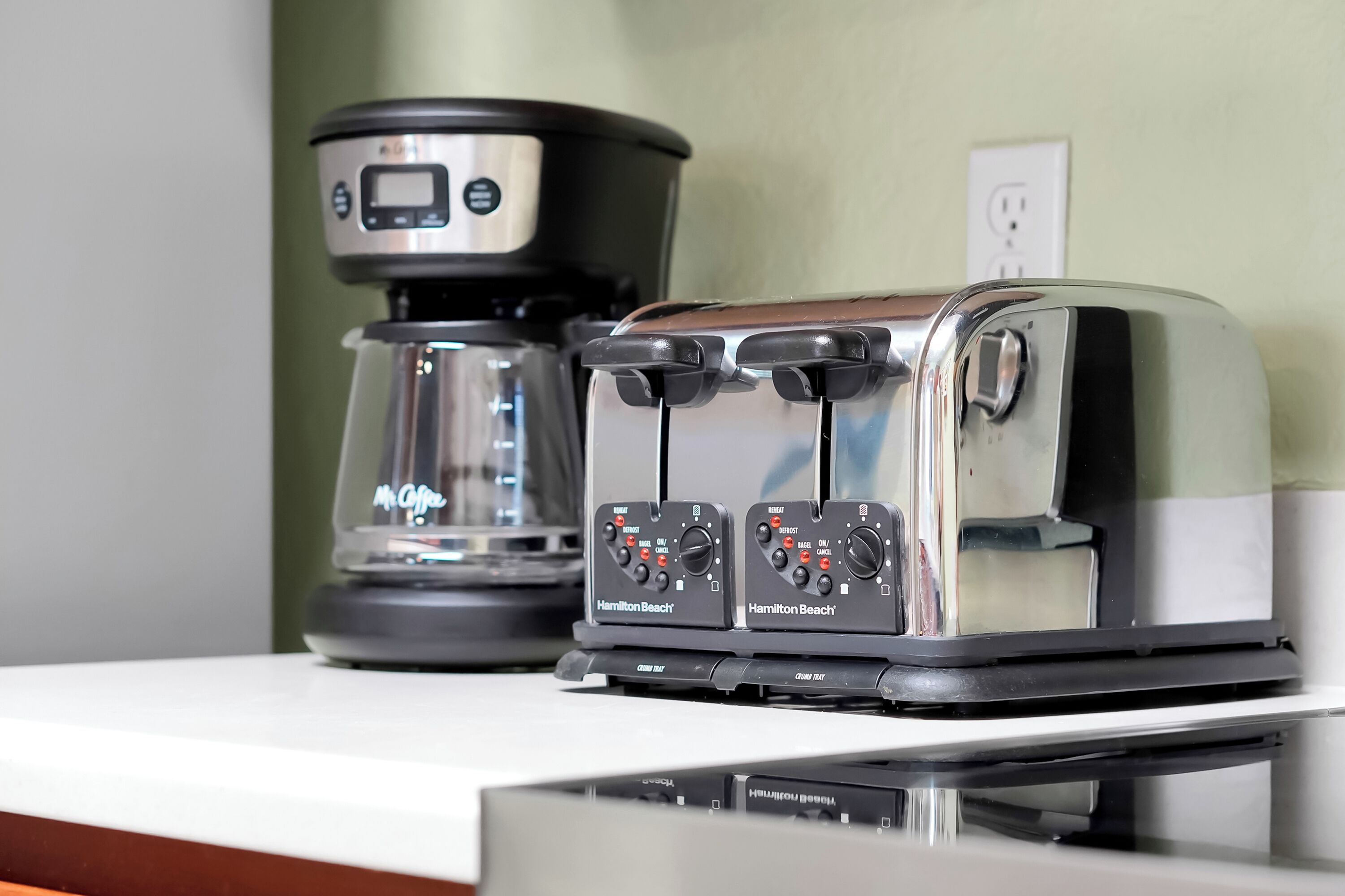 Eine Küche mit einer Kaffeemaschine und zwei Hamilton Beach Toastern auf einer Arbeitsfläche.