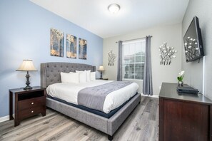 Een slaapkamer met een groot bed, twee nachtkastjes, een kaptafel en kunstwerken aan de muur.