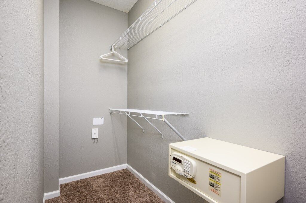 A laundry room with a white washing machine, a drying rack, and a wall-mounted drying rack.