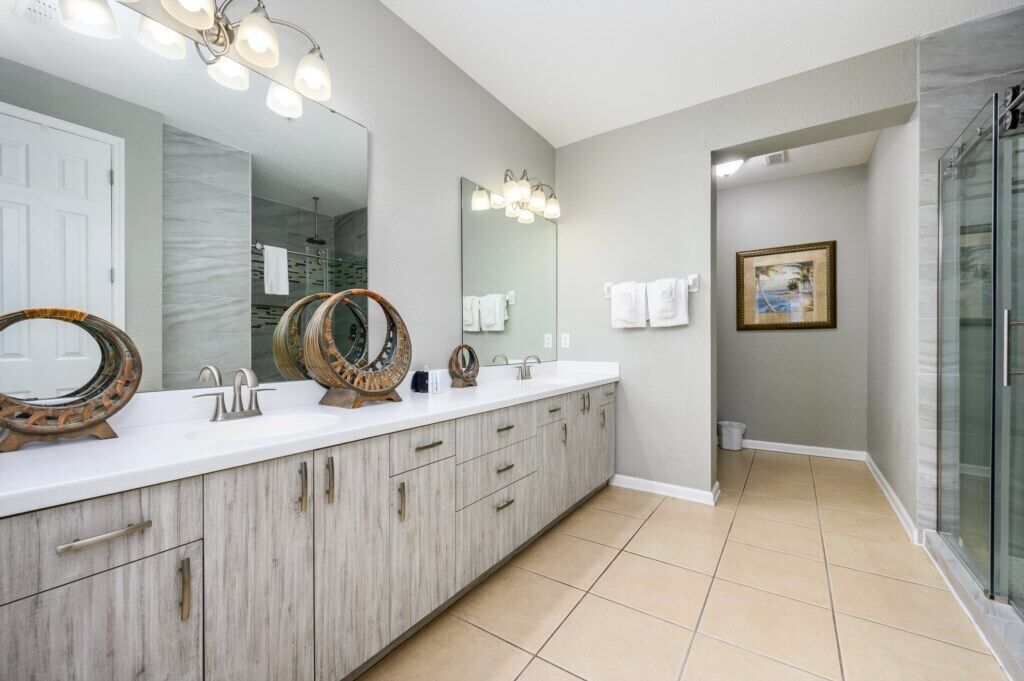 A modern bathroom with a large vanity, two sinks, and a glass shower enclosure.