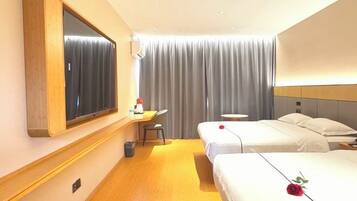 Habitación de hotel con dos camas, un escritorio, una silla, un espejo y un ventanal grande con cortinas.