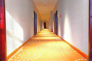A hotel corridor with a patterned carpet, doors on both sides, and a fire extinguisher on the wall. - Mingya Hotel (Bohai International Plaza) (Binzhou)