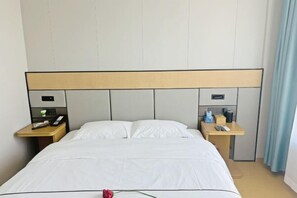A hotel room with a large bed, two bedside tables, a headboard, and a nightstand with a phone and a remote control. - Mingya Hotel (Bohai International Plaza) (Binzhou)