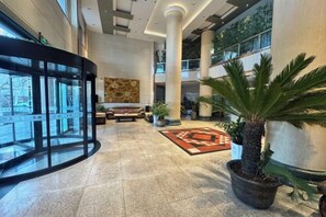 Vestíbulo con mostrador de recepción, zona de estar y plantas en macetas.