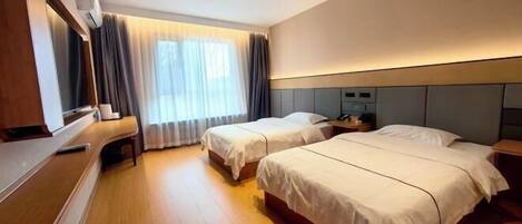 A hotel room with two beds, a desk, and a TV.