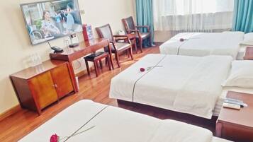 Habitación de hotel con dos camas, un escritorio y televisión.