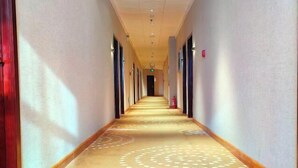 A hotel corridor with patterned carpet, doors on both sides, and a fire extinguisher on the right wall. - Mingya Hotel (Bohai International Plaza) (Binzhou)