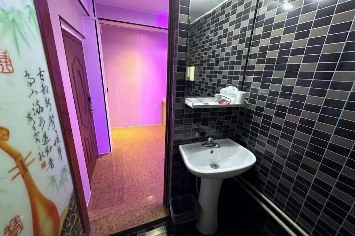A bathroom with a sink, tiled walls, and a door leading to another room.