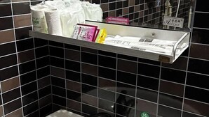 A bathroom with black tiled walls, a white sink, and a shelf with various toiletries. - Nanning City Hui Hotel (Jiuquwan Hot Spring) (Nanning)
