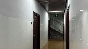 A corridor with white tiled walls, a wooden door, and a staircase with metal railings. - Nanning City Hui Hotel (Jiuquwan Hot Spring) (Nanning)