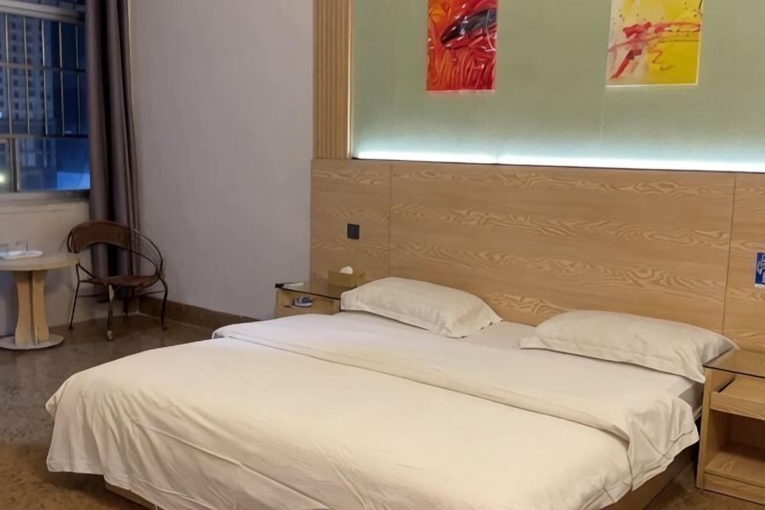 Camera d'albergo con un letto grande, un tavolino, una sedia e un comodino.