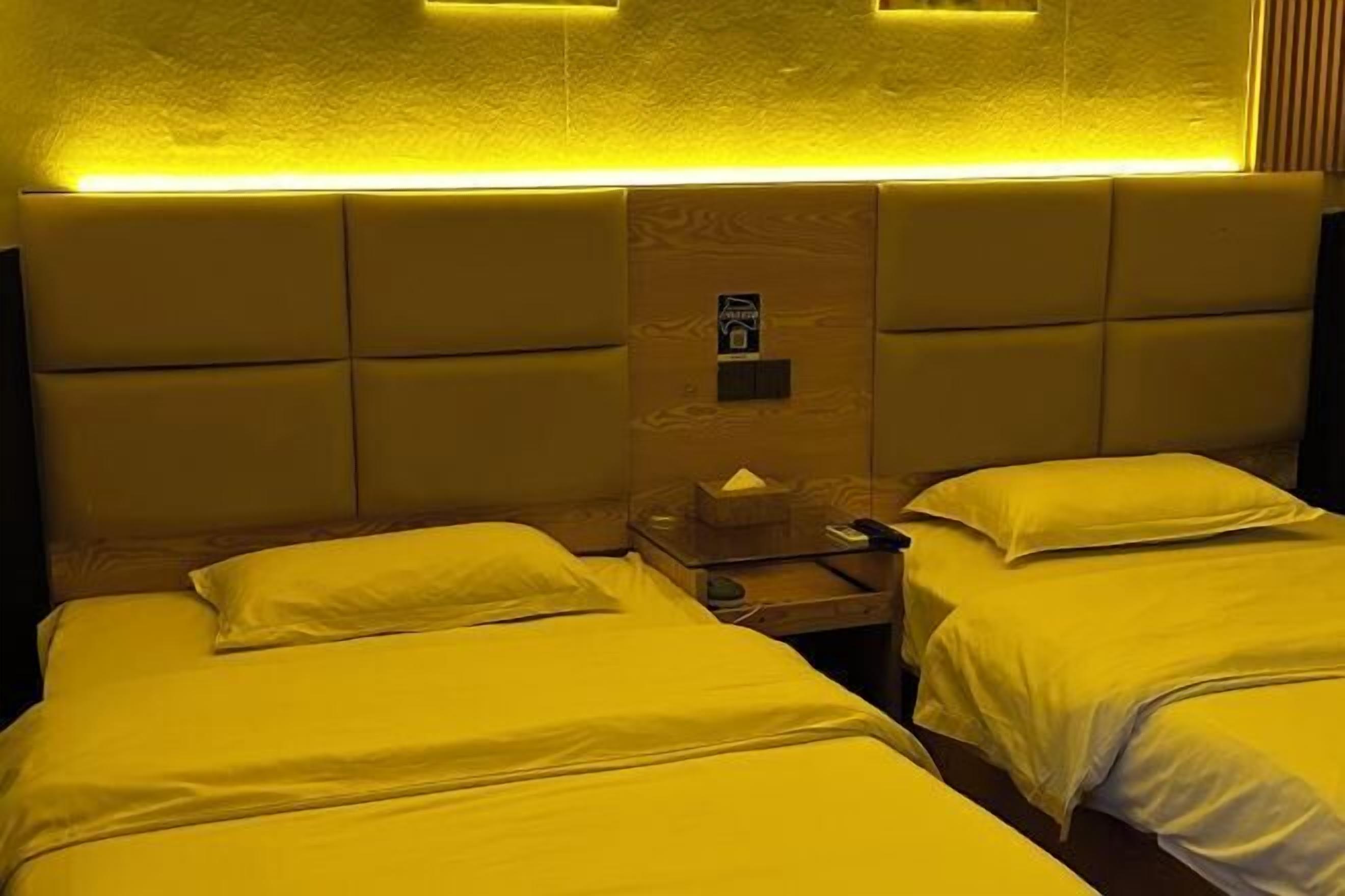 A hotel room with two beds, each with a pillow and a wooden nightstand.