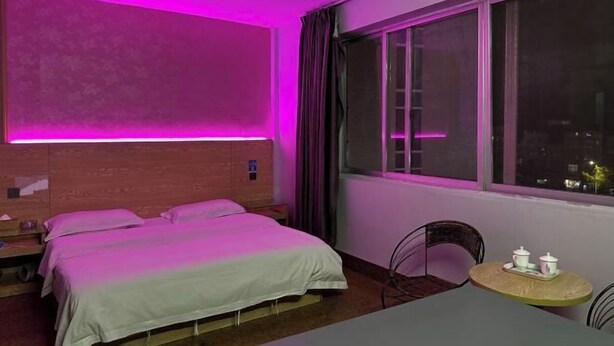 A hotel room with a bed, a small table with cups, and a window with curtains. - Nanning City Hui Hotel (Jiuquwan Hot Spring) (Nanning)