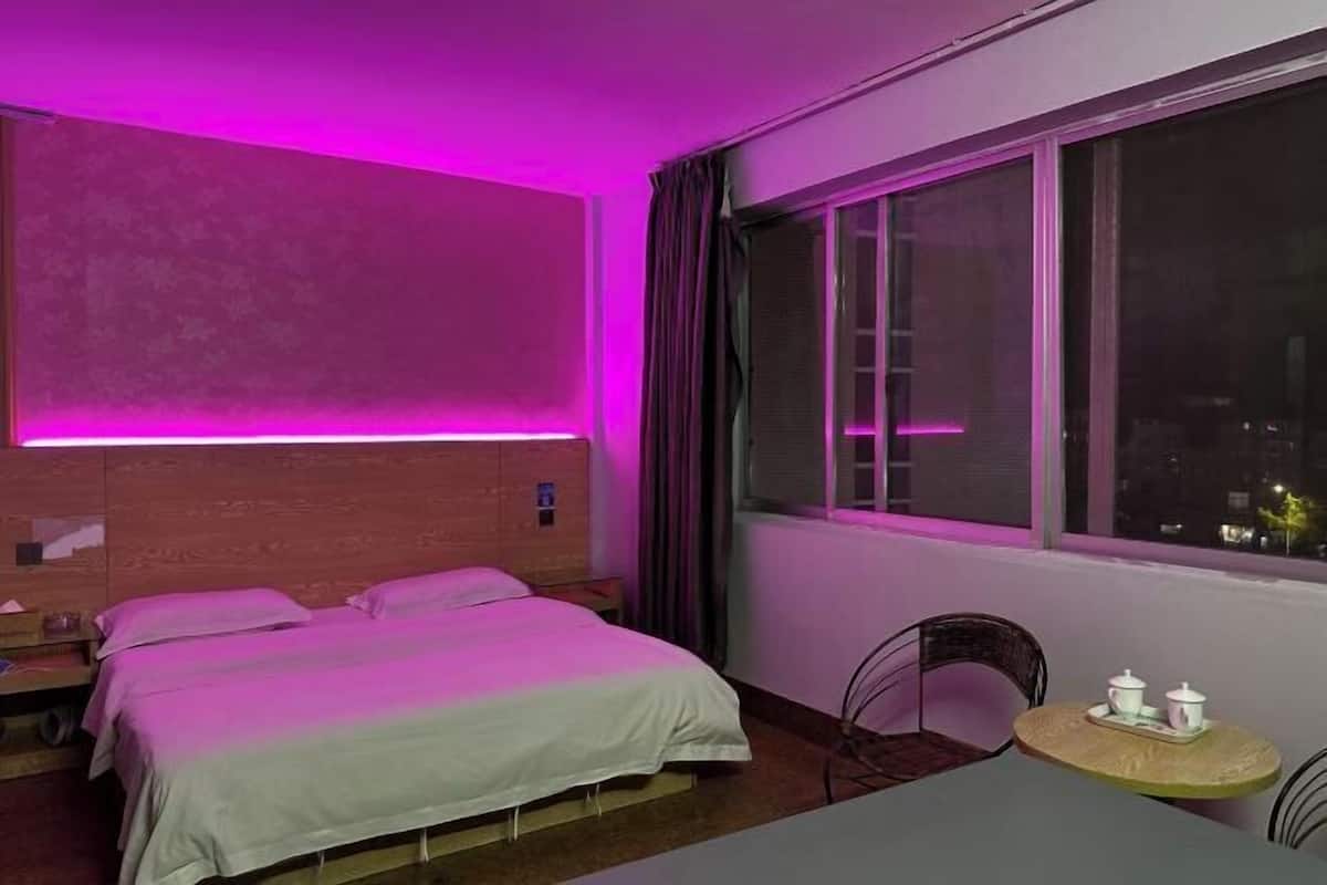 A hotel room with a bed, a small table with cups, and a window with curtains.