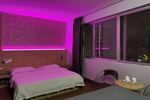 Una habitación de hotel con una cama, una mesita con tazas y un ventanal con cortinas.