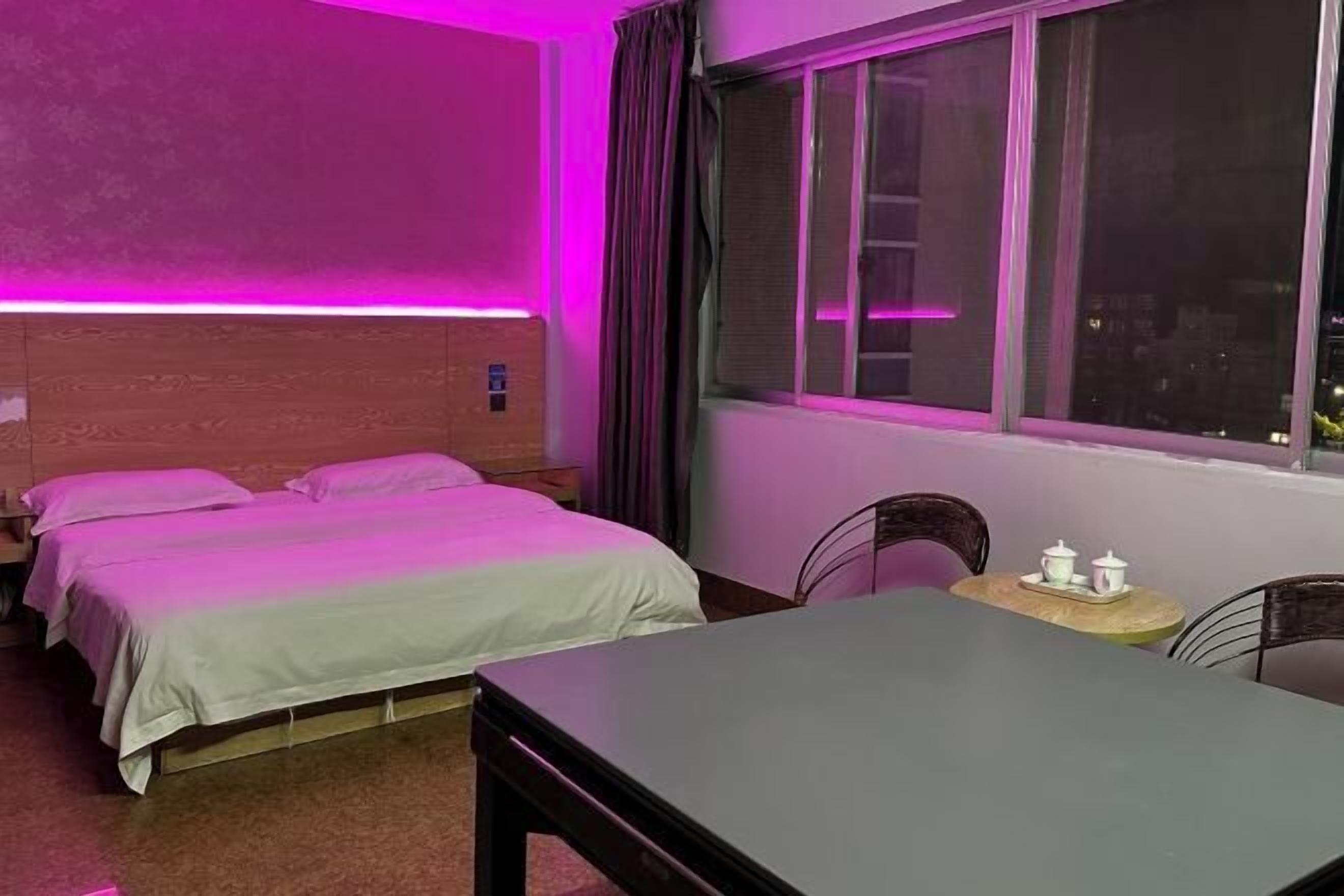 Une chambre d’hôtel avec deux lits, une table et une fenêtre avec des rideaux.