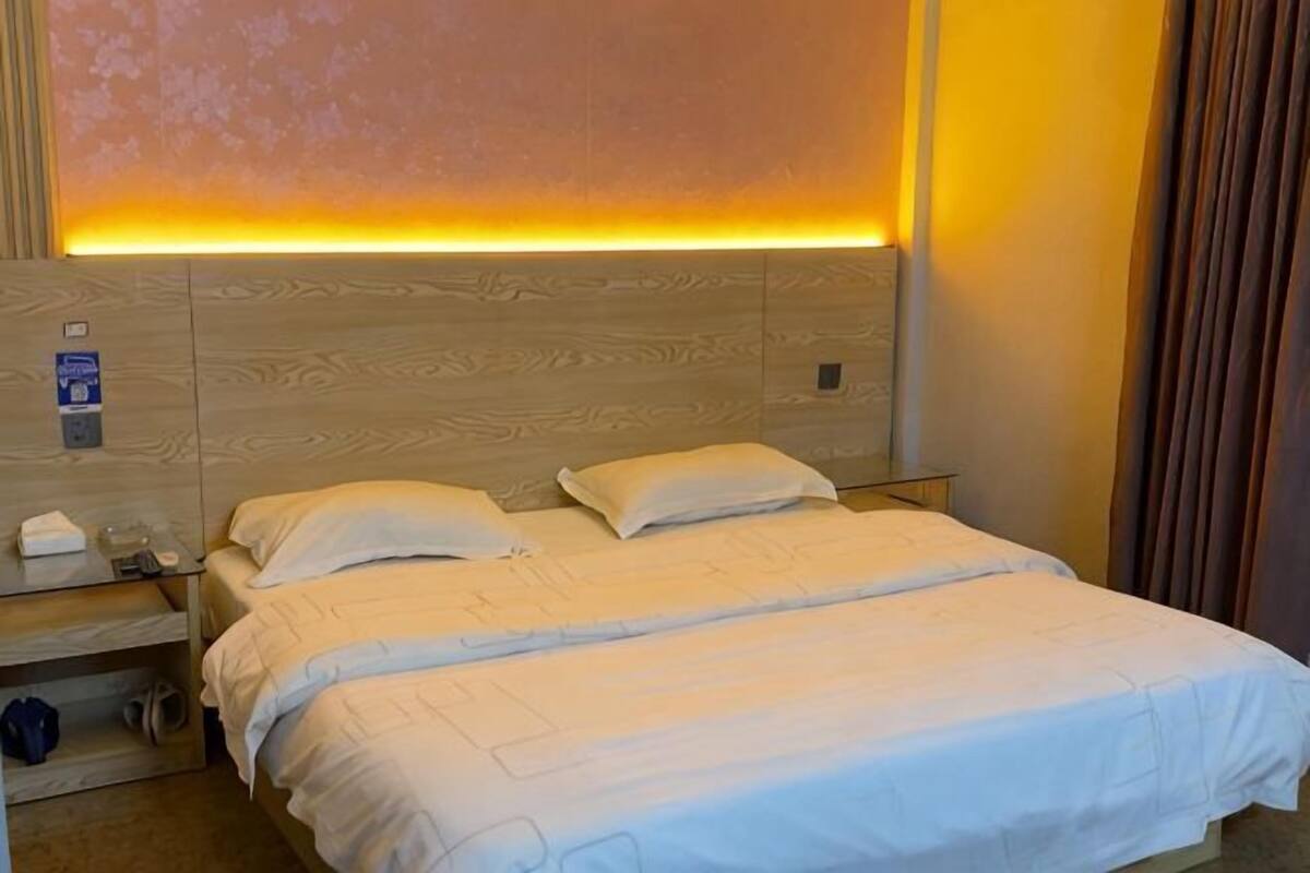 A hotel room with a bed, bedside tables, and a headboard with built-in lighting.