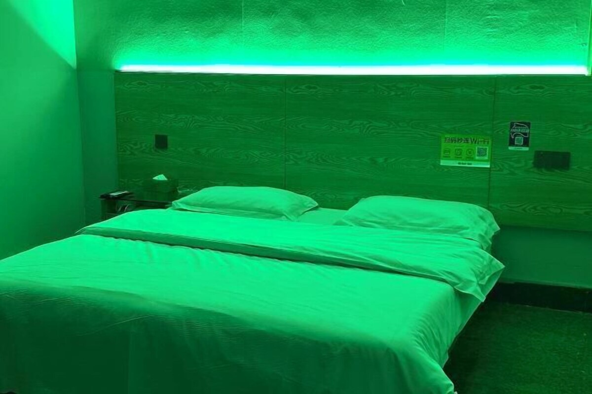 A room with a bed, a nightstand, and a wall-mounted sign.