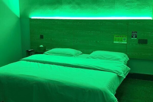 A room with a bed, a nightstand, and a wall-mounted sign.
