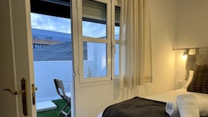 Habitación de hotel con cama, ventana y vista a un edificio.
