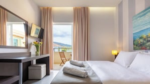 Een hotelkamer met een bed, een bureau, een stoel, een televisie en een schilderij aan de muur.