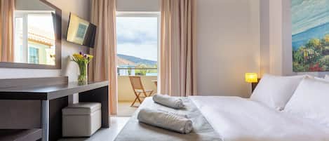 Et hotelværelse med seng, skrivebord, stol, fjernsyn og et billede på væggen.