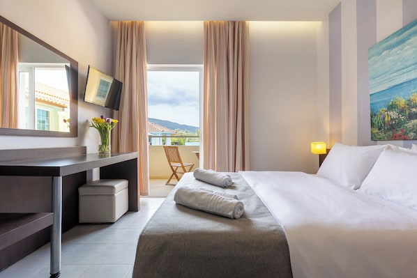 Una camera d'albergo con un letto, una scrivania, una sedia, una TV e un quadro appeso al muro.