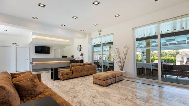 Een moderne woonkamer met een bank, poef en een flatscreen televisie.