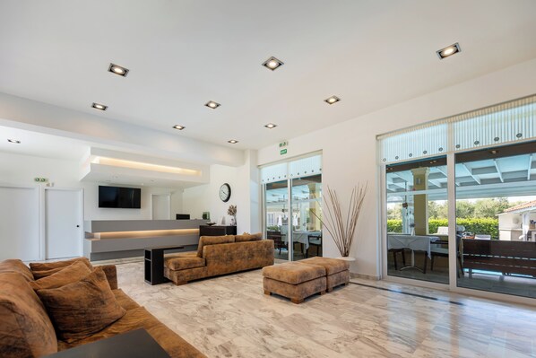 Een moderne woonkamer met een bank, poef en een flatscreen televisie.