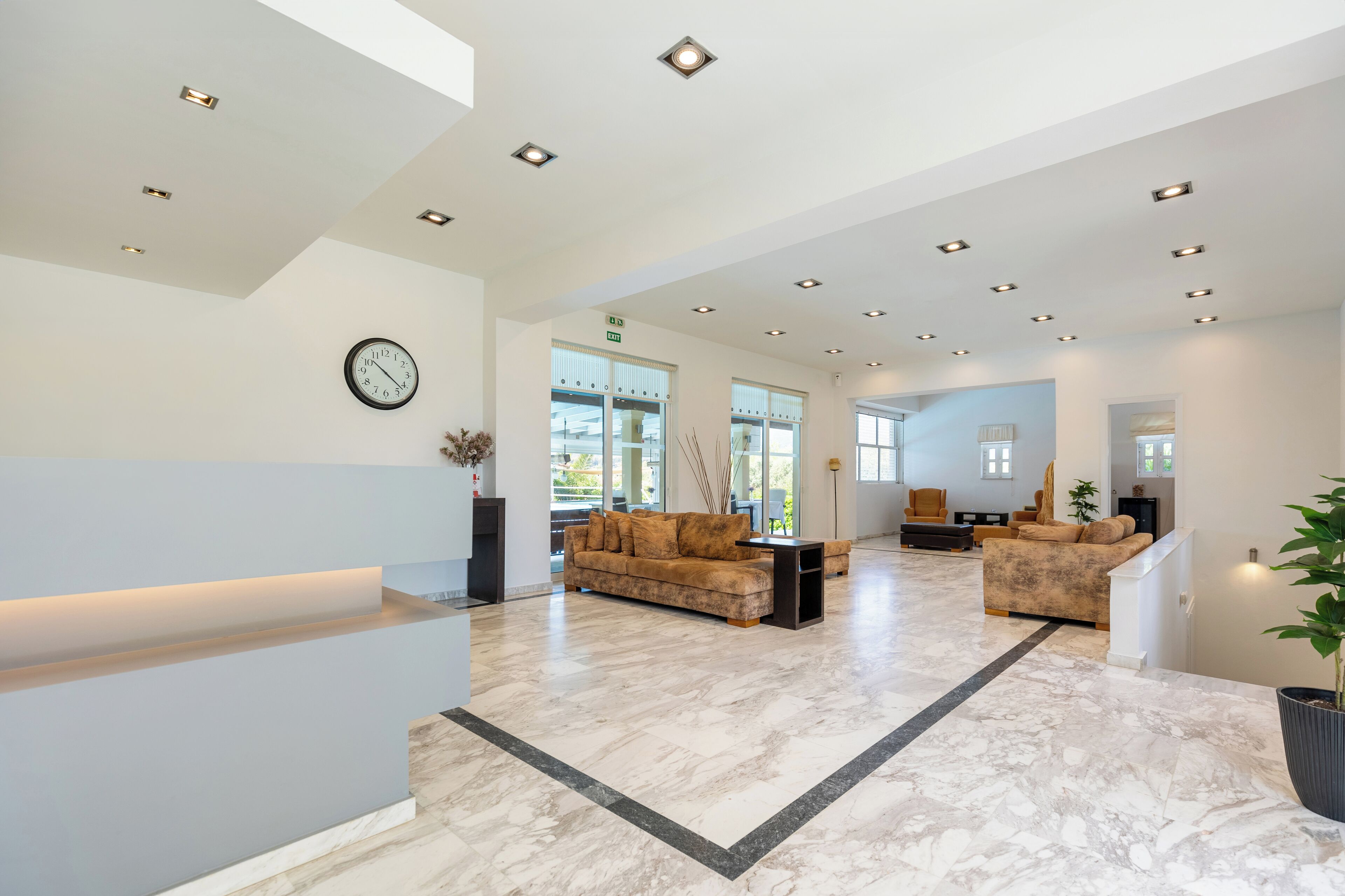 A spacious lobby with a marble floor, a reception desk, and two sofas.