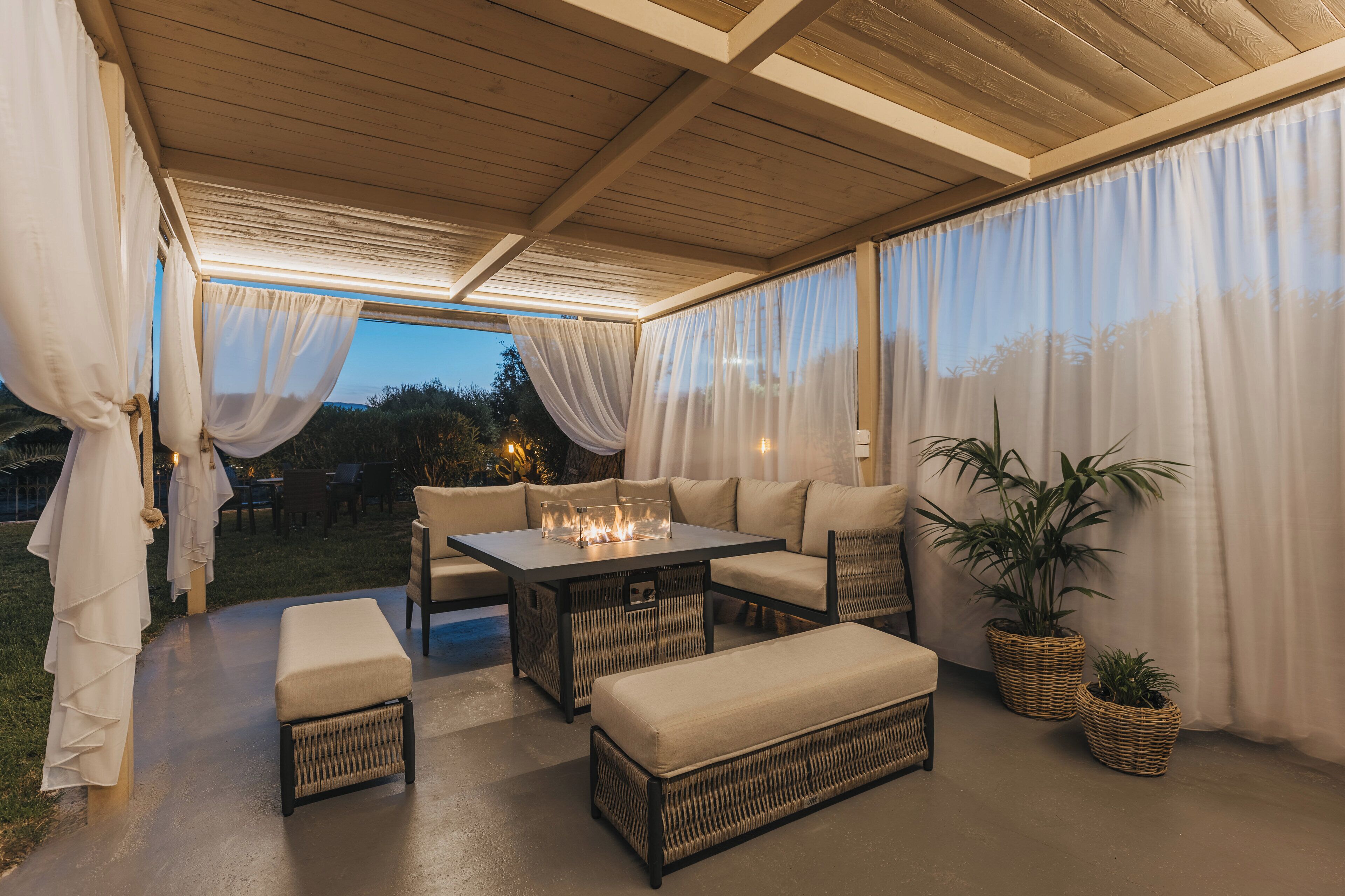 An outdoor patio with a fire feature, seating, and potted plants.