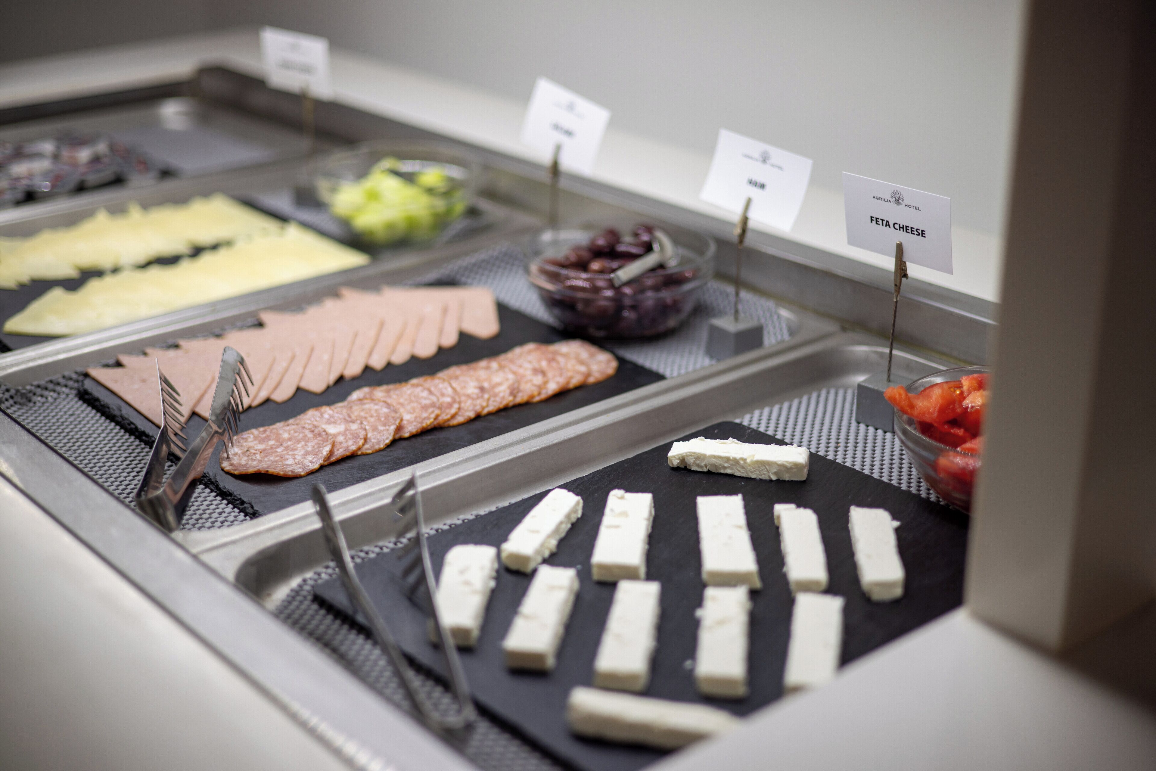 A buffet with various food options including meats, cheeses, and fruits.