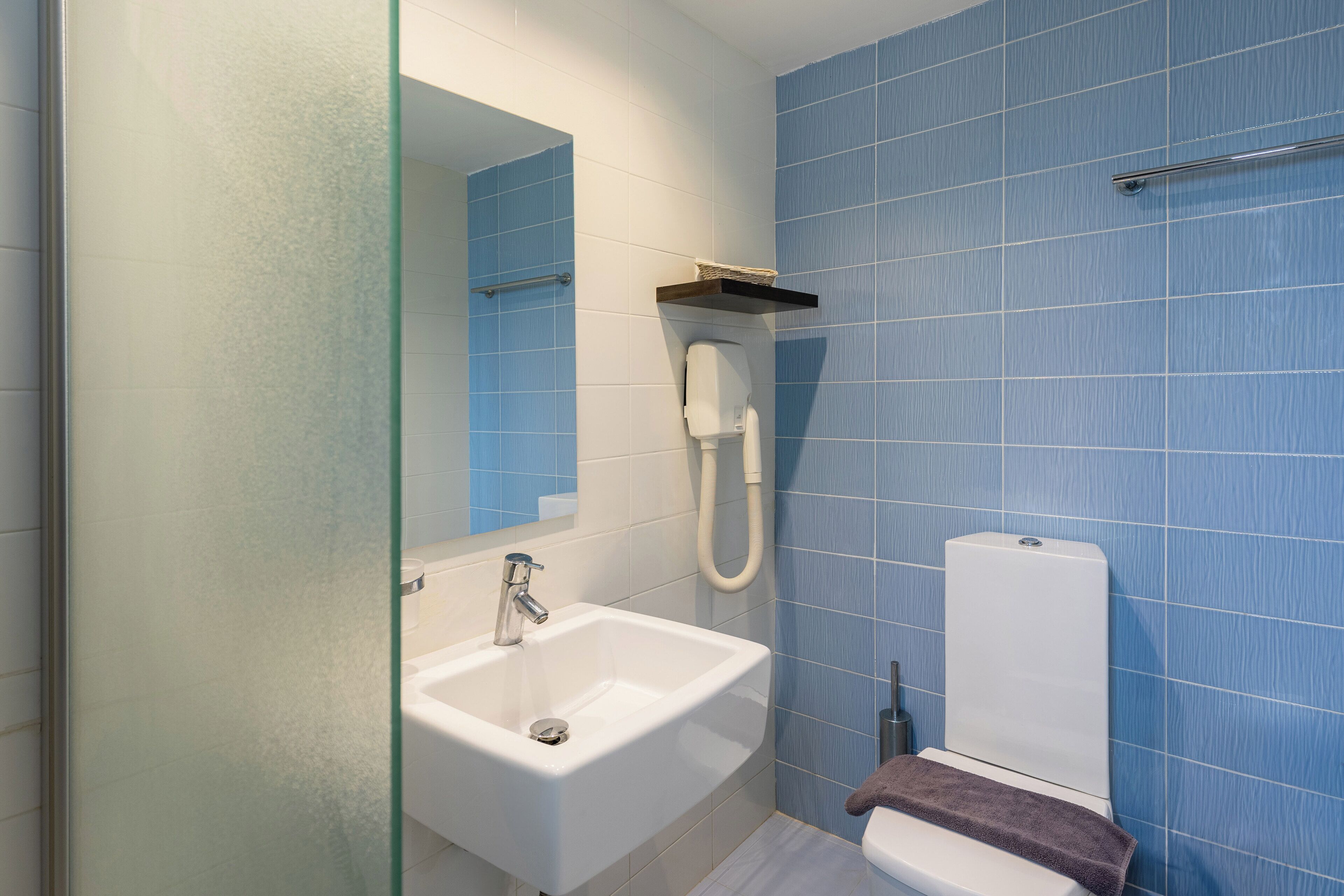 A bathroom with a white sink, a glass shower enclosure, and a toilet.