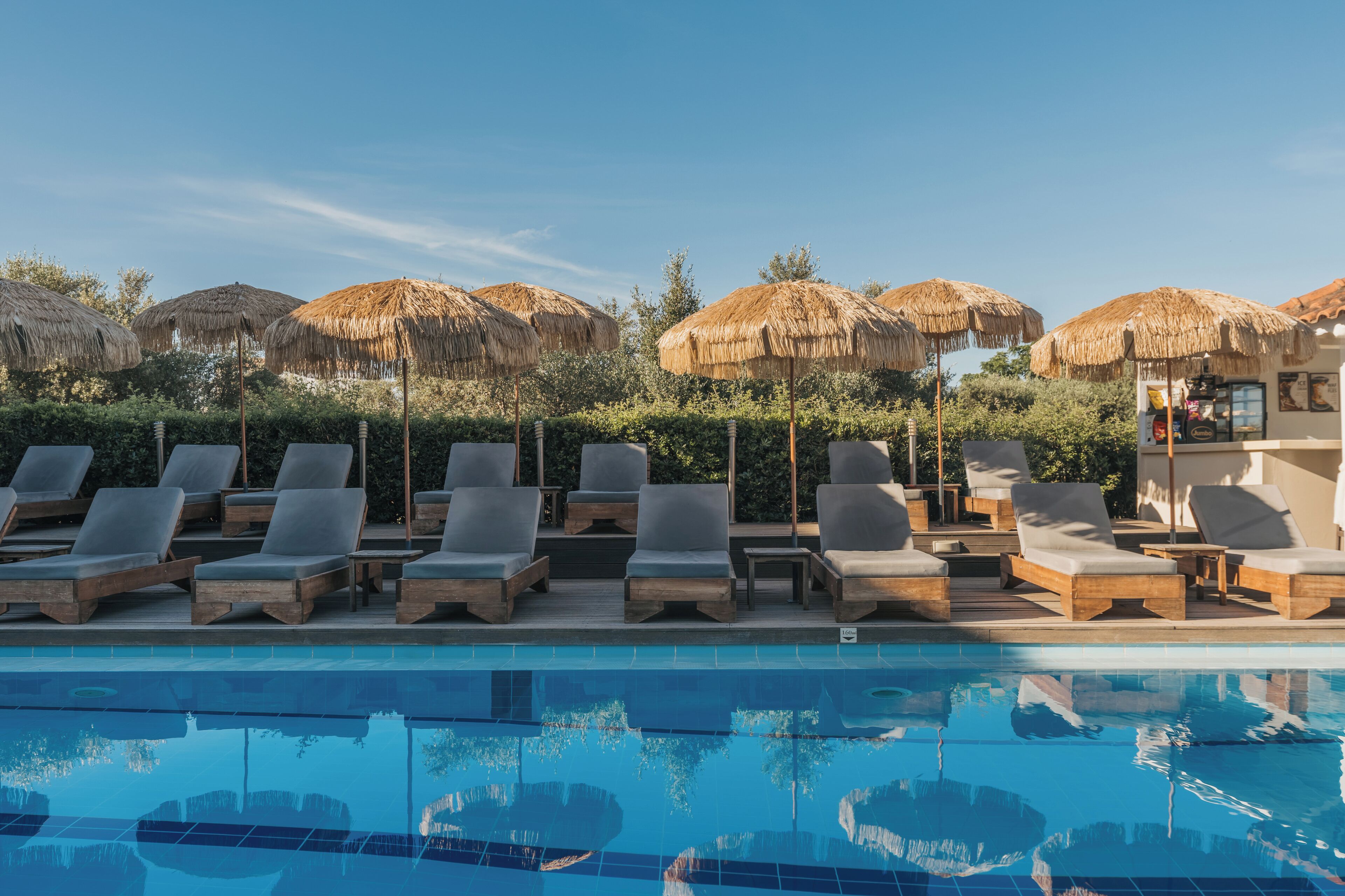 A poolside area with lounge chairs and thatched umbrellas.