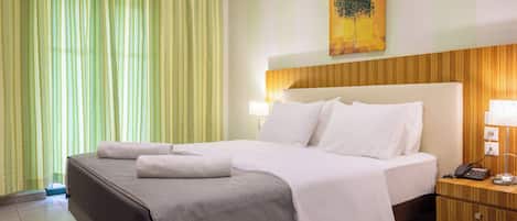 A hotel room with a large bed, a nightstand with a lamp, and a painting on the wall.