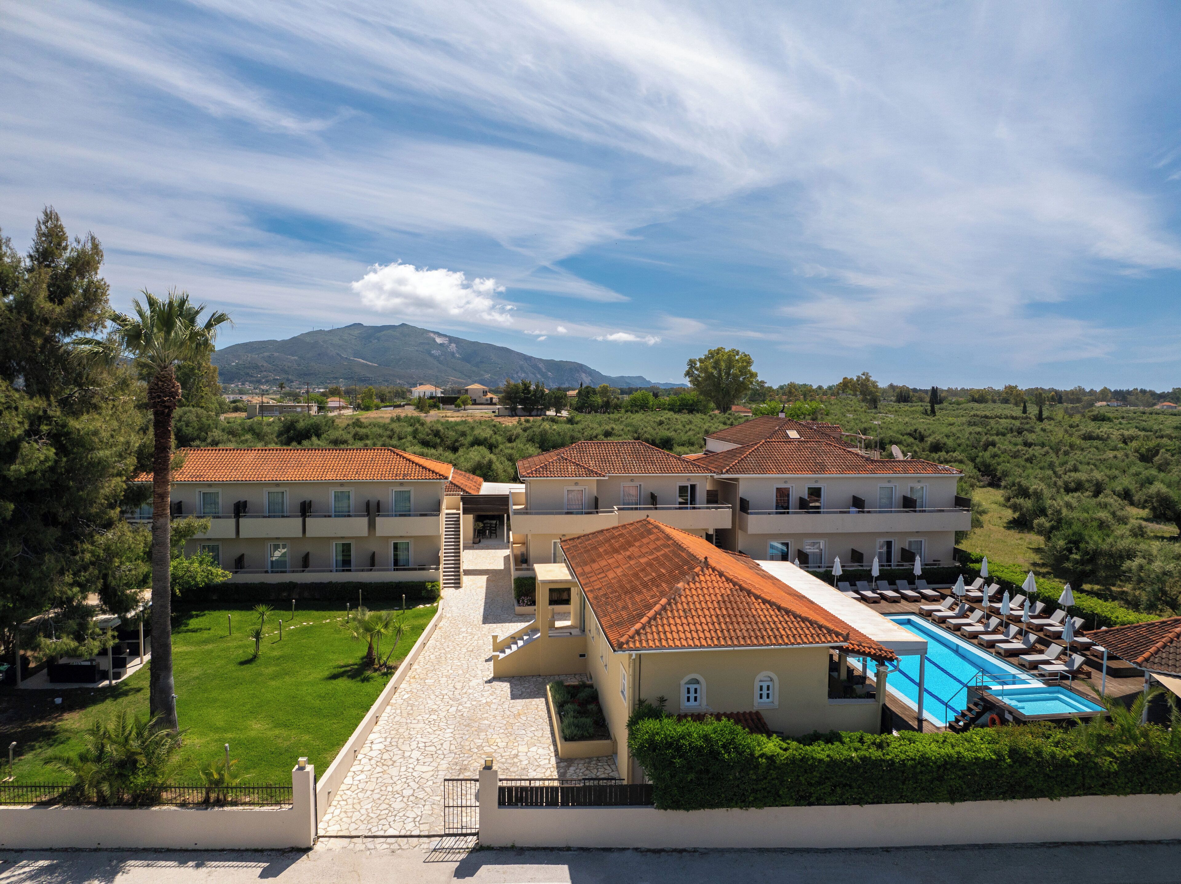 A resort with multiple buildings, a swimming pool, and a mountainous backdrop.