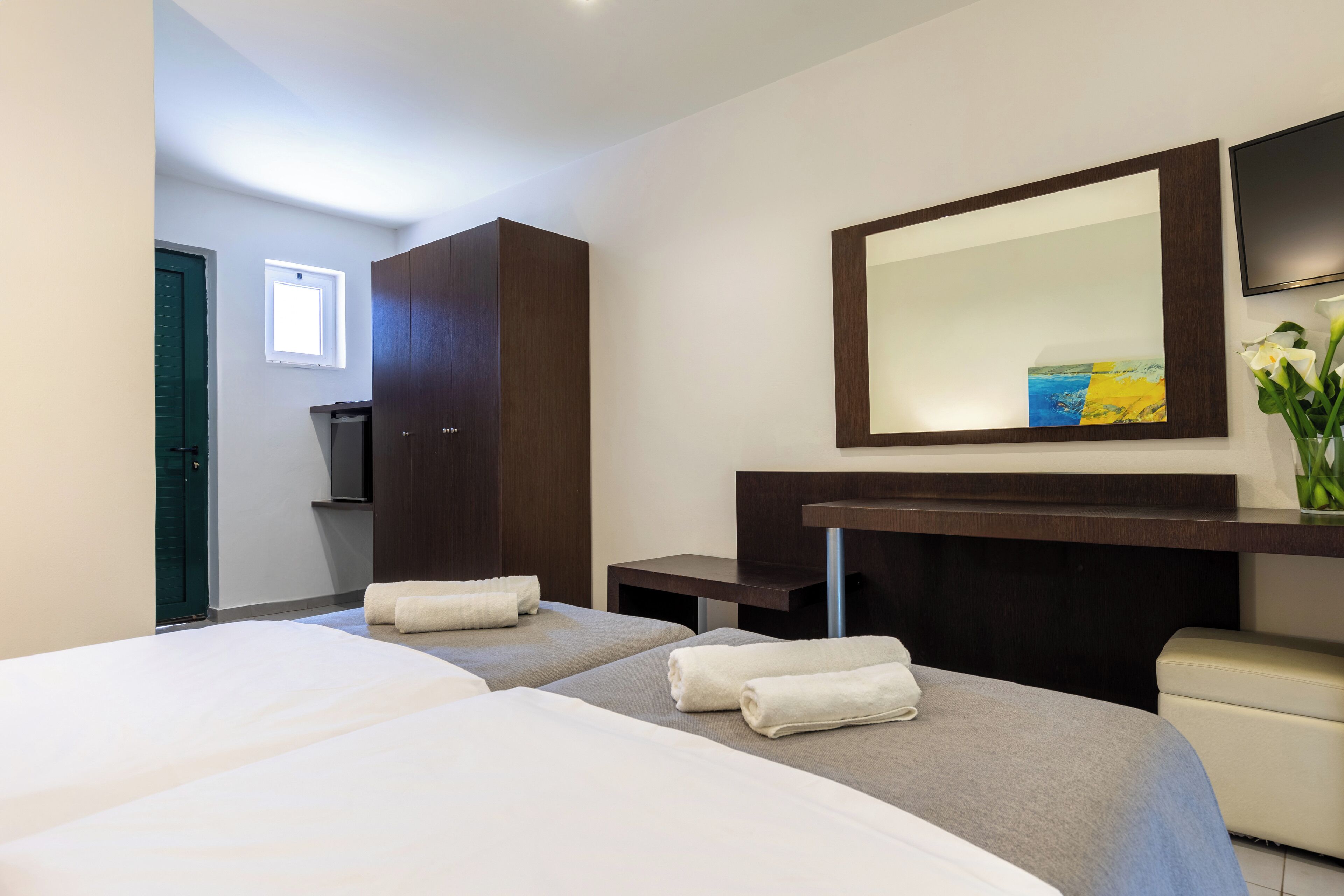 Een hotelkamer met twee bedden, een grote spiegel, een televisie en een klein tafeltje.
