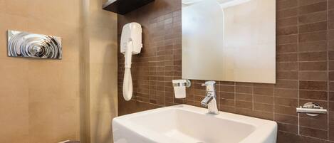 A bathroom with a white sink, a towel rack, a hand dryer, and a mirror.