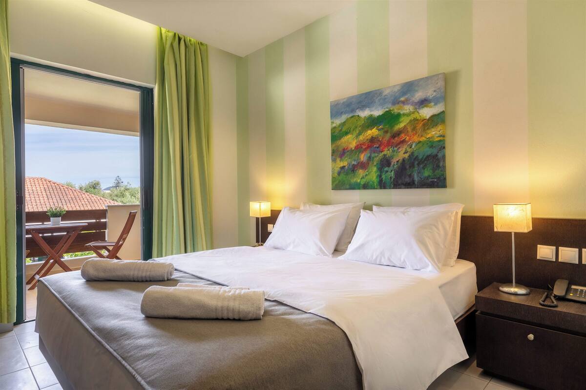 Een hotelkamer met een bed, bedlampen, een schilderij aan de muur en uitzicht op de omgeving.