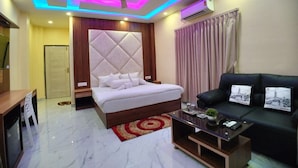 Una habitación de hotel moderna con una cama, un sofá, una mesa de centro y un ventilador de techo.