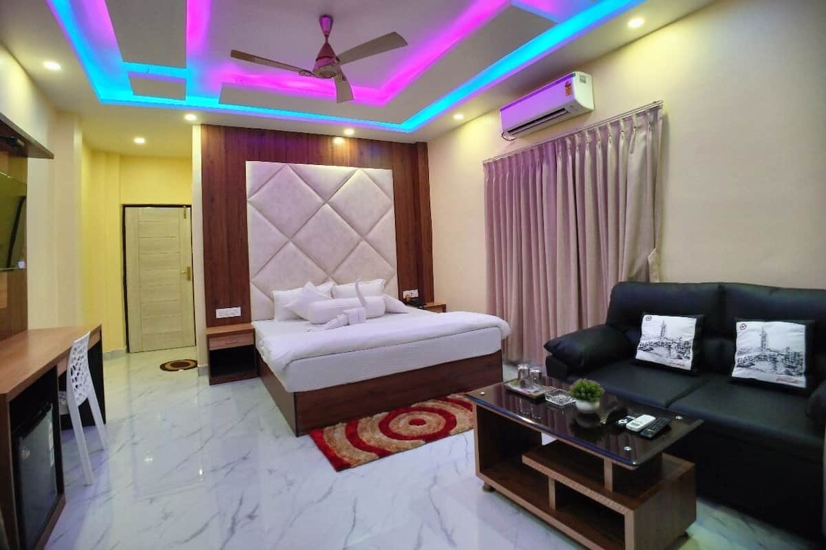 A modern hotel room with a bed, a sofa, a coffee table, and a ceiling fan.